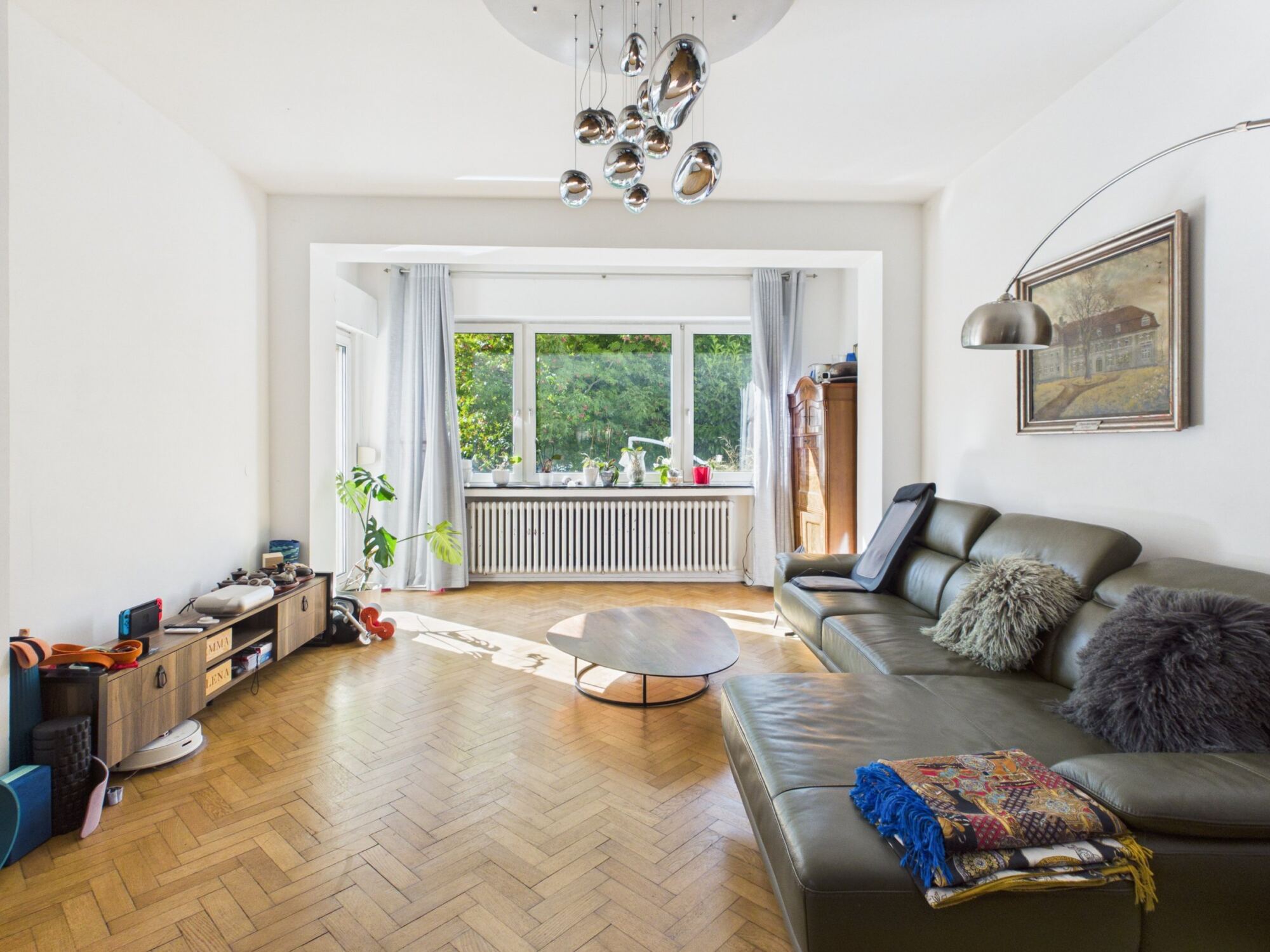 Wohnzimmer mit Fischgrätparkett und Blick ins Grüne